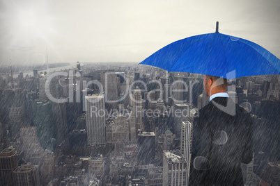 Composite image of rear view of businessman holding blue umbrella and briefcase