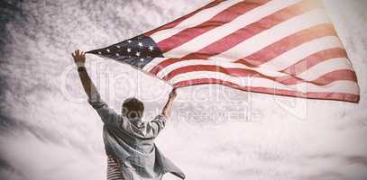 Low angle view of man holding american flag against cloudy sky