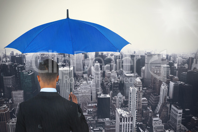 Composite image of rear view of businessman carrying blue umbrella