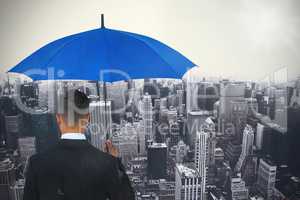 Composite image of rear view of businessman carrying blue umbrella