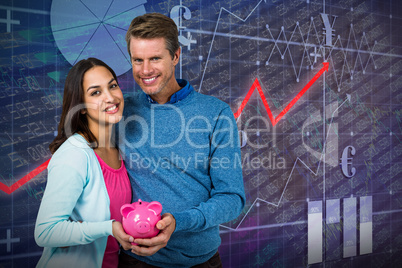 Composite image of smiling couple holding piggy bank