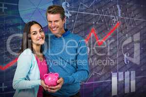 Composite image of smiling couple holding piggy bank