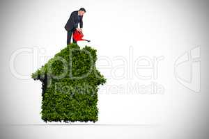 Composite image of mature businessman using watering can