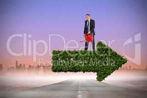 Composite image of businessman holding red watering can