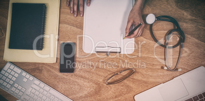 Overhead view of doctor writing on clipboard at desk