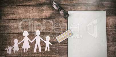 Paper cut out family chain with medicine and file on table