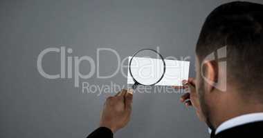 Composite image of rear view of man holding magnifying glass on paper