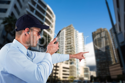 Composite image of security officer pointing away while talking on walkie talkie