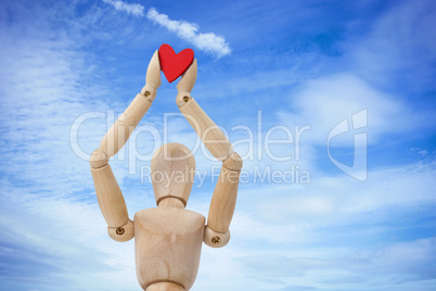 Composite image of wooden three dimensional figurine holdingred heart on top