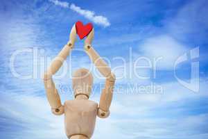 Composite image of wooden three dimensional figurine holdingred heart on top
