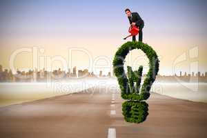 Composite image of businessman watering with red can