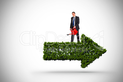 Composite image of businessman holding red watering can