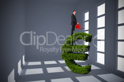 Composite image of businessman holding red watering can