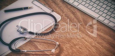 High angle view of stethoscope with clipboard by wireless keyboard and mouse
