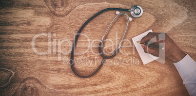 Doctor writing prescription on notepad at desk