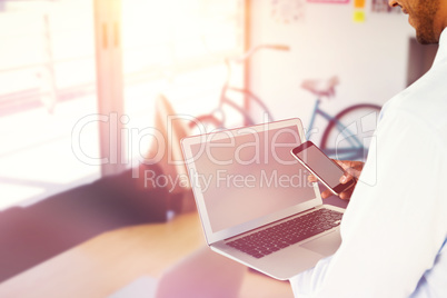 Composite image of side view of businessman using mobile phone and laptop