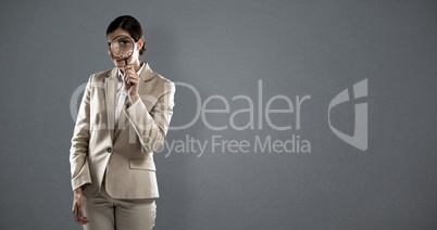 Composite image of businesswoman looking through magnifying glass