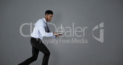 Composite image of businessman using laptop while running