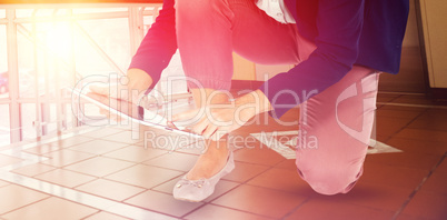 Composite image of low section of businesswoman kneeling while using digital tablet