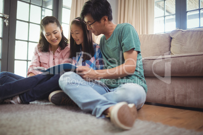 Family watching photo album together in living room