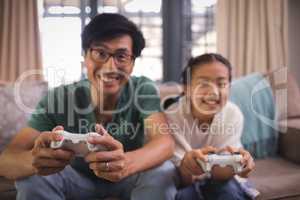 Father and daughter playing video game in living room