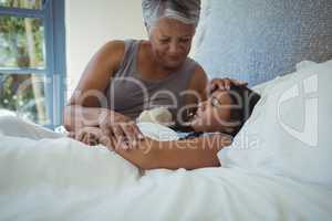 Grandmother comforting sick granddaughter in bed room