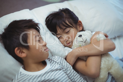 Siblings sleeping on bed in the bed room