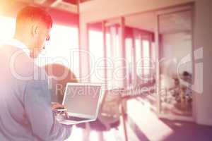 Composite image of focused businessman using laptop