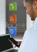 Businessman holding phone with apps icons in room