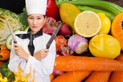 Chief holding knifes with a vegetables background