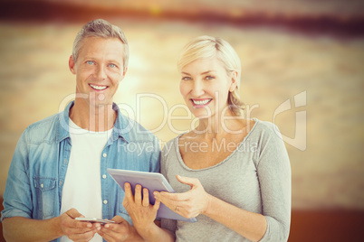 Composite image of portrait of couple with digital tablet and mobile phone