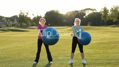 Smiling adult women doing ab exercises with balls