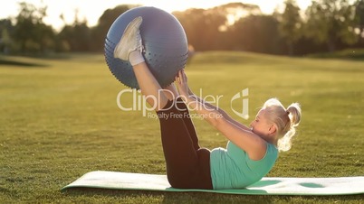 Adult woman making exercise with fitball in park