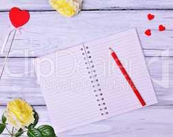 Open blank notebook and red wooden pencil