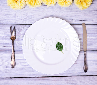 Empty white plate and metal fork and knife