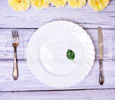 Empty white plate and metal fork and knife