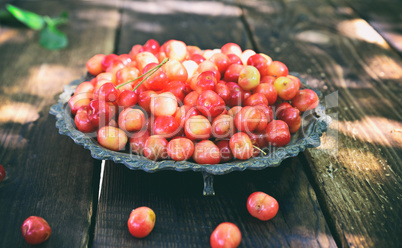 Pink cherry in a metal plate on a wooden table