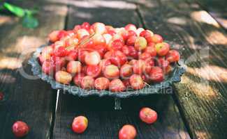 Pink cherry in a metal plate on a wooden table