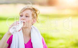 Young Fit Adult Woman Outdoors with Towel Drinking From Her Wate