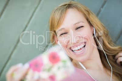 Young Adult Woman Wearing Earphones Taking a Selfie with Her Sma