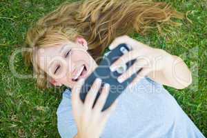 Young Adult Woman Laying in Grass Taking a Selfie with Her Smart