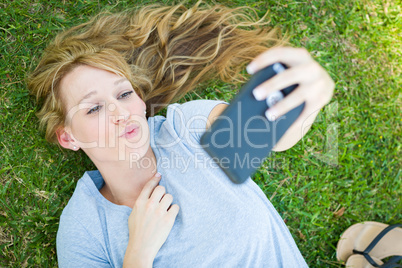 Young Adult Woman Laying in Grass Taking a Selfie with Her Smart