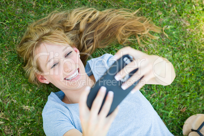 Young Adult Woman Laying in Grass Taking a Selfie with Her Smart