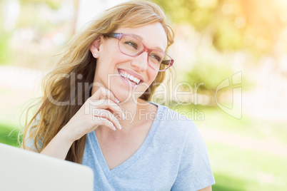 Young Adult Woman Wearing Glasses Outdoors Using Her Laptop.