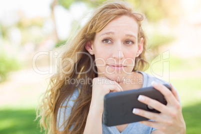 Concerned Young Woman Outdoors Looking At Her Smart Phone.