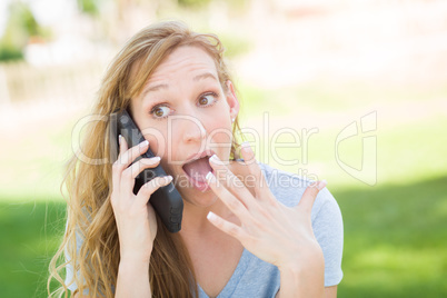 Stunned Young Woman Outdoors Talking on Her Smart Phone.