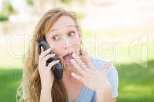 Stunned Young Woman Outdoors Talking on Her Smart Phone.