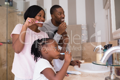 Parents with children brushing teeth in bathroom at home