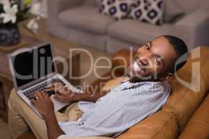 Portrait of happy young man using laptop at home
