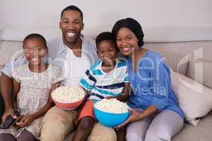 Cheerful family with popcorn bowls siting on sofa